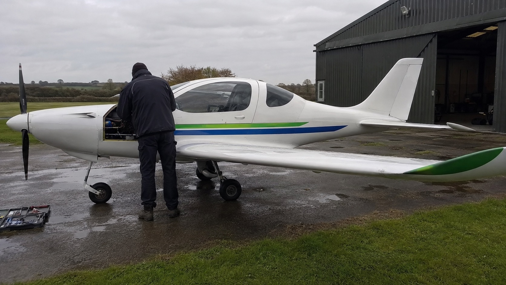 Engineer inspecting a hybrid-electric test aircraft outside a rural hangar